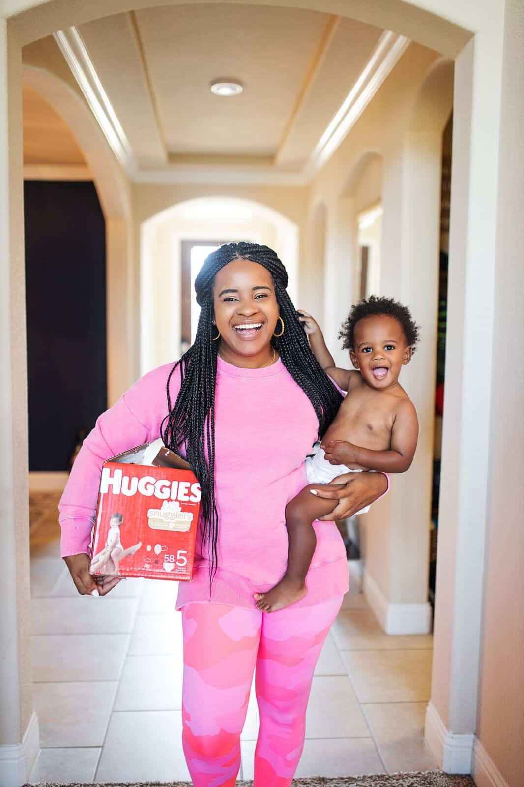 Basic Toddler Essentials by popular life and style blog, Glamorous Versatility: image of a woman holding a box of Huggies diapers and her baby.