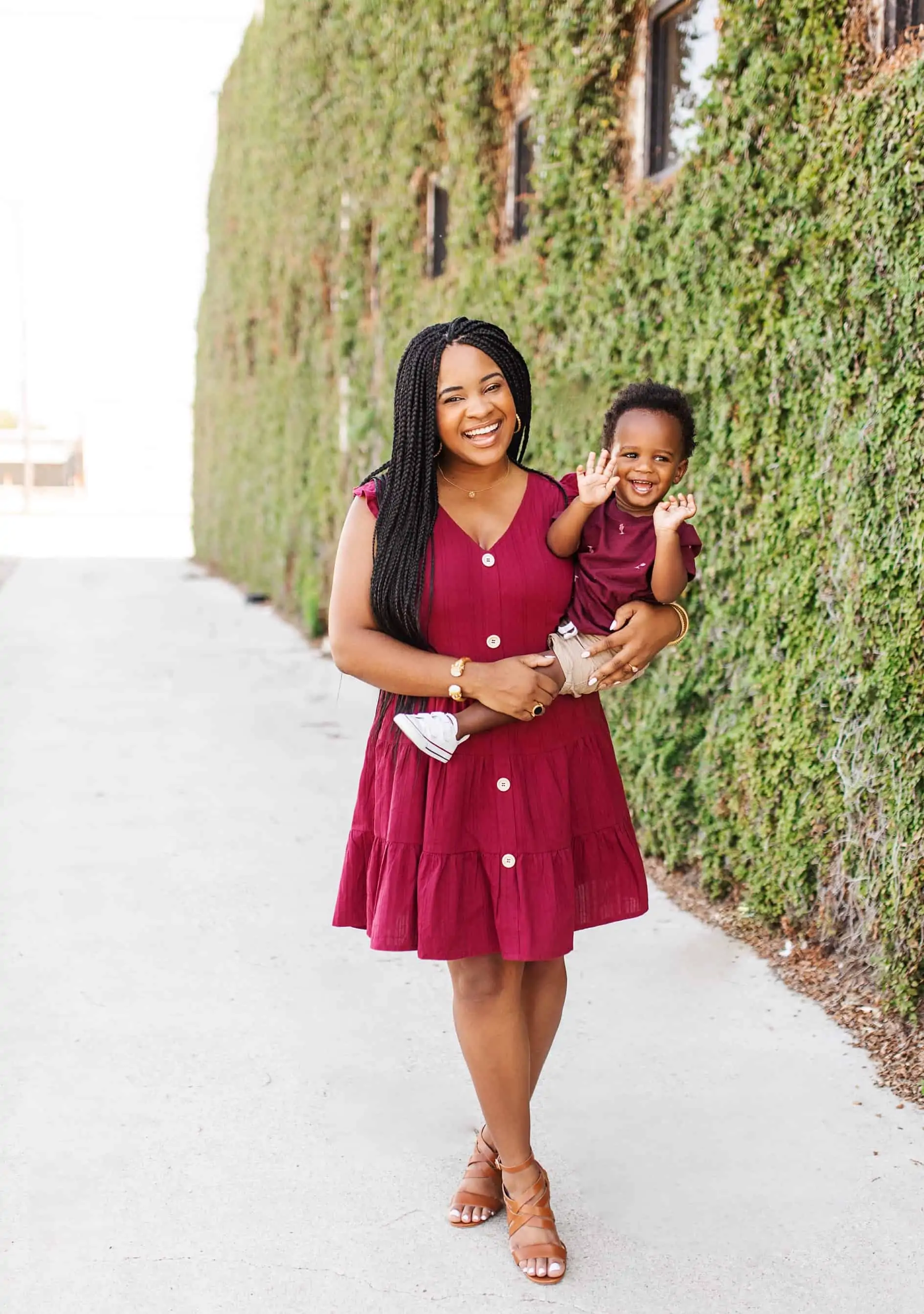My Breastfeeding Essentials & Journey by popular Dallas life and style blog, Glamorous Versatility: image of a woman standing outside by a building covered in ivy and holding her baby boy.