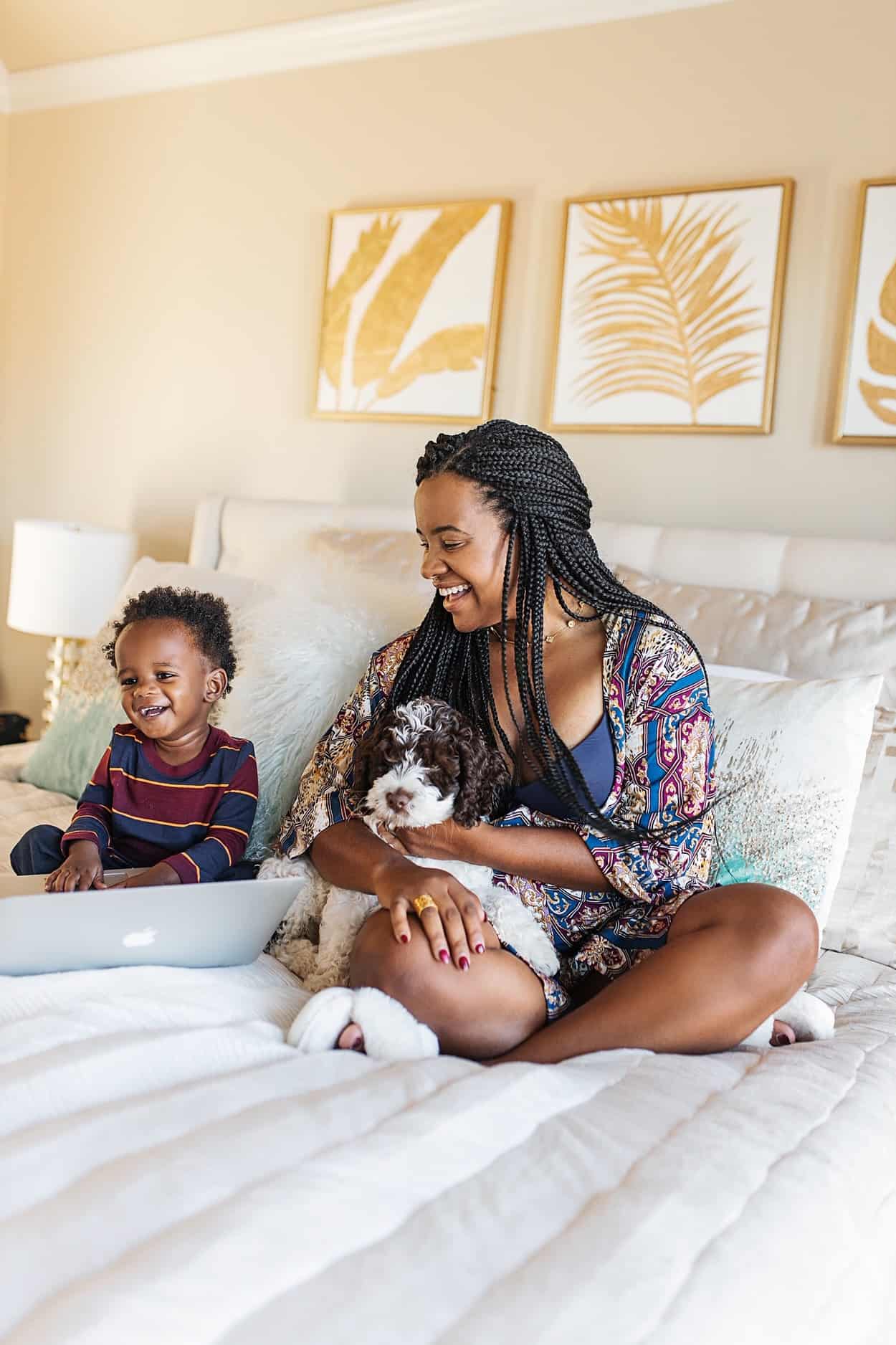 Why I Love Soma Enbliss by popular fashion blog, Glamorous Versatility: image of a woman holding a small dog and sitting on a bed with her young son and wearing a Soma wireless Enbliss bra.