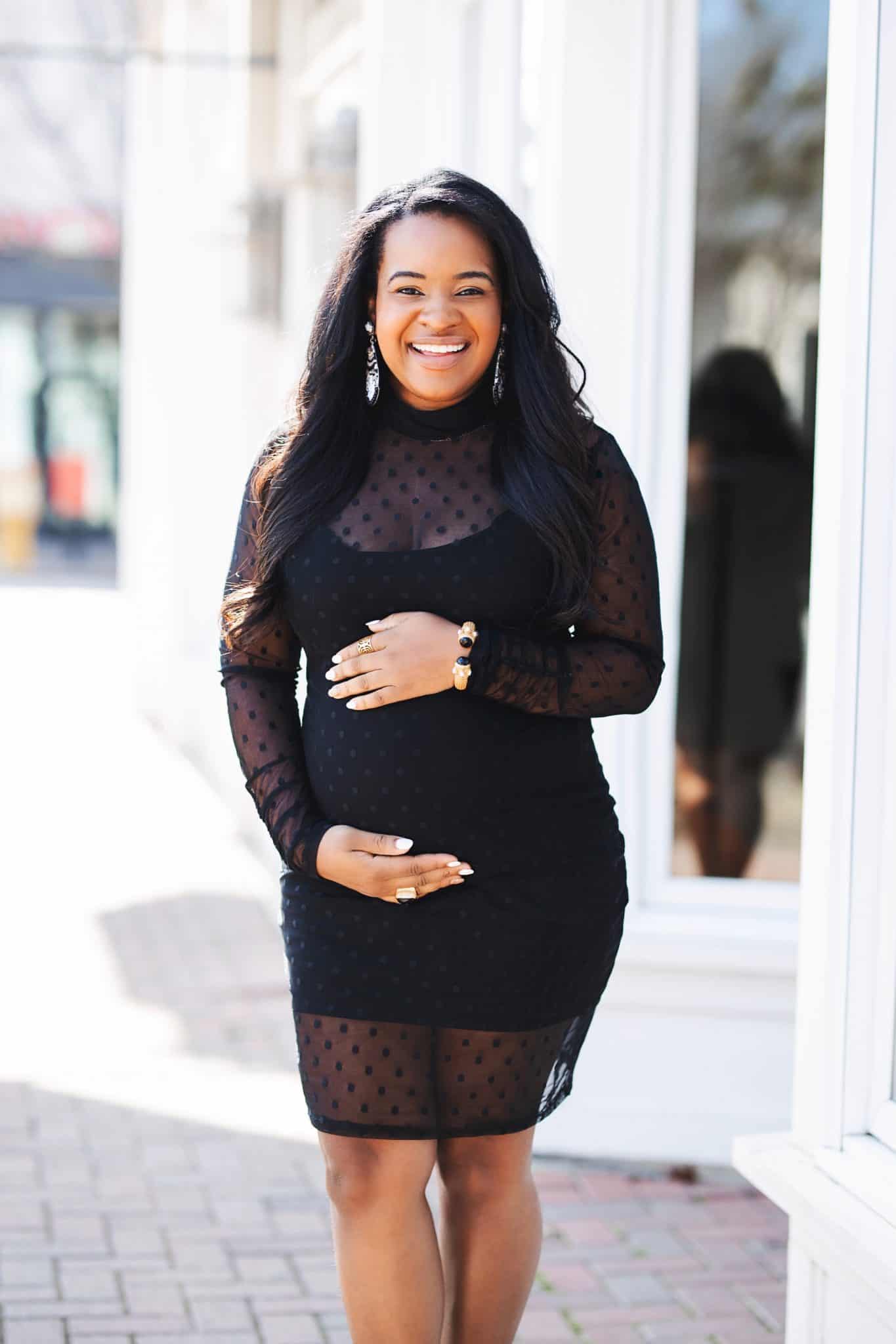Valentine's Day Dresses in Every Budget by popular Dallas fashion blog, Glamorous Versatility: image of a woman wearing a black mesh polka dot dress and holding her pregnant belly.