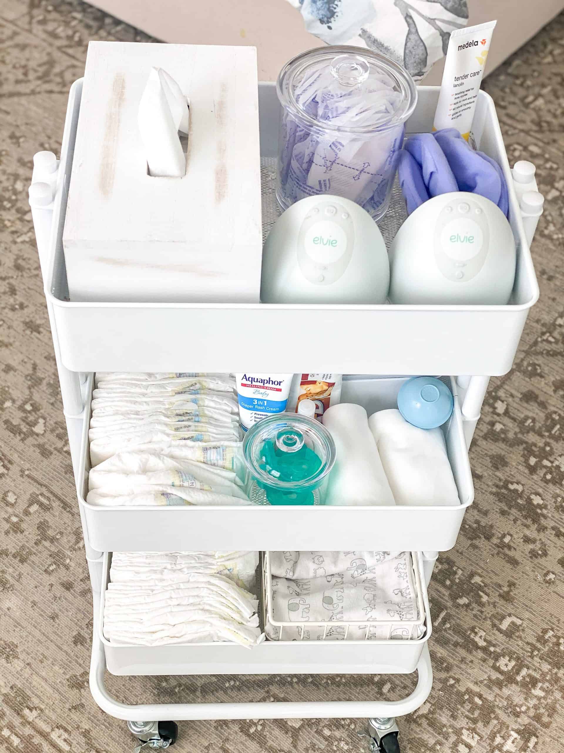 Newborn Cart by popular Dallas motherhood blog, Glamorous Versatility: image of a The Container Store White 3-Tier Rolling Cart, The Container Store White Stacking Wire Bins, Target Ubbi Wipes Dispenser, The Container Store Bliss Acrylic Canisters, The Container Store iDesign Linus Shallow Drawer Organizers, diapers, binkies, Aquaphor, A + D ointment, and burp cloths.  