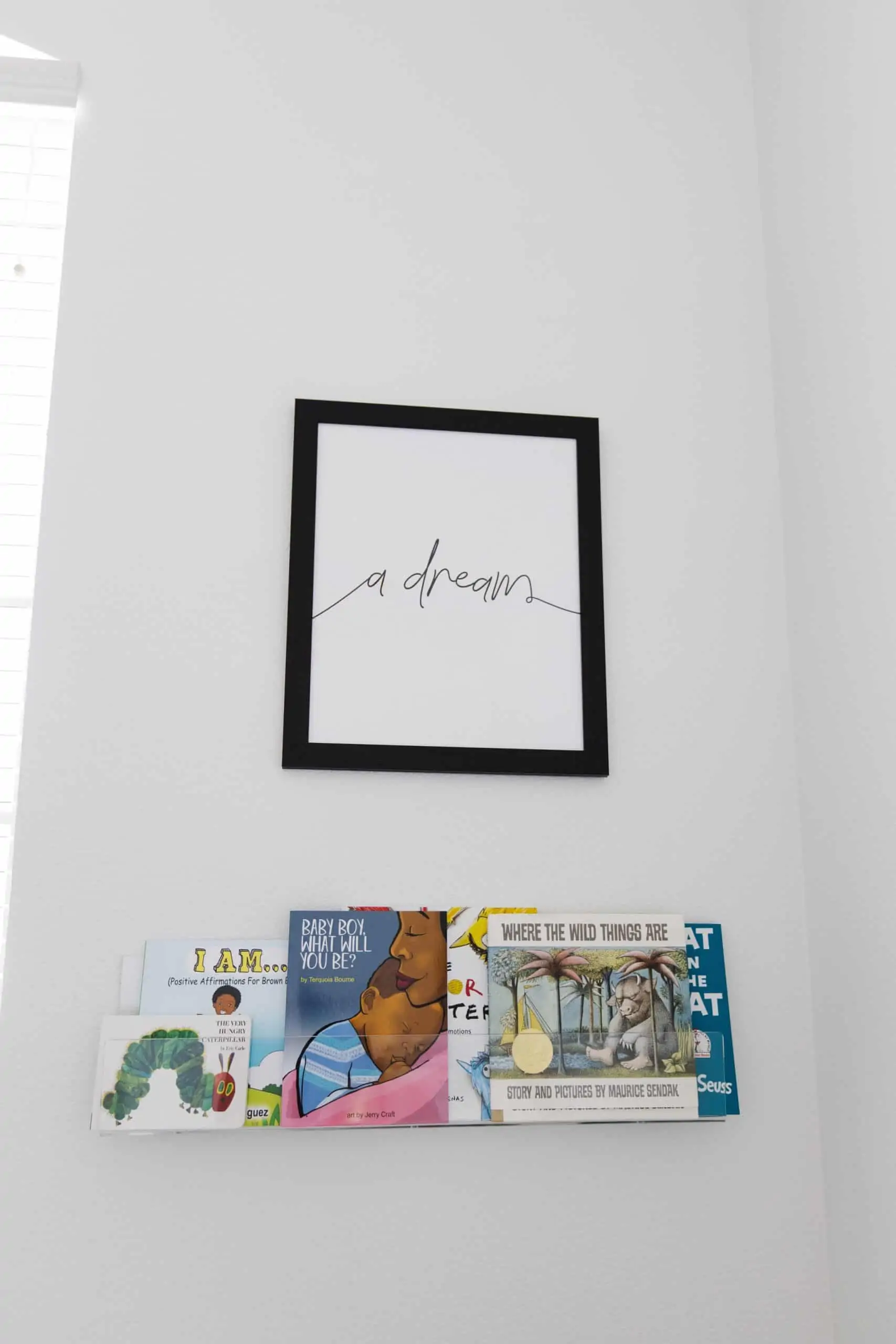 Baby Nursery by popular Dallas life and style blog, Glamorous Versatility: image of a baby nursery decorated with a Biggie Smalls Wall Trio, various picture books and acrylic wall mounted book shelf. 