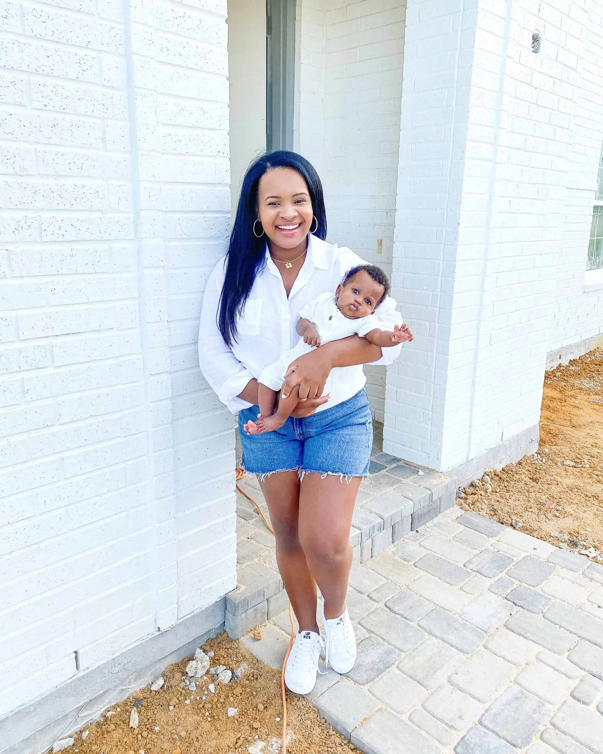 Working Mom by popular Dallas lifestyle blog, Glamorous Versatility: image of a woman wearing a white button down t-shirt, Walmart Sofia Jeans By Sofia Vergara and Walmart Athletic Works Women’s Soft Running Sneakers while holding her baby in her arms. 