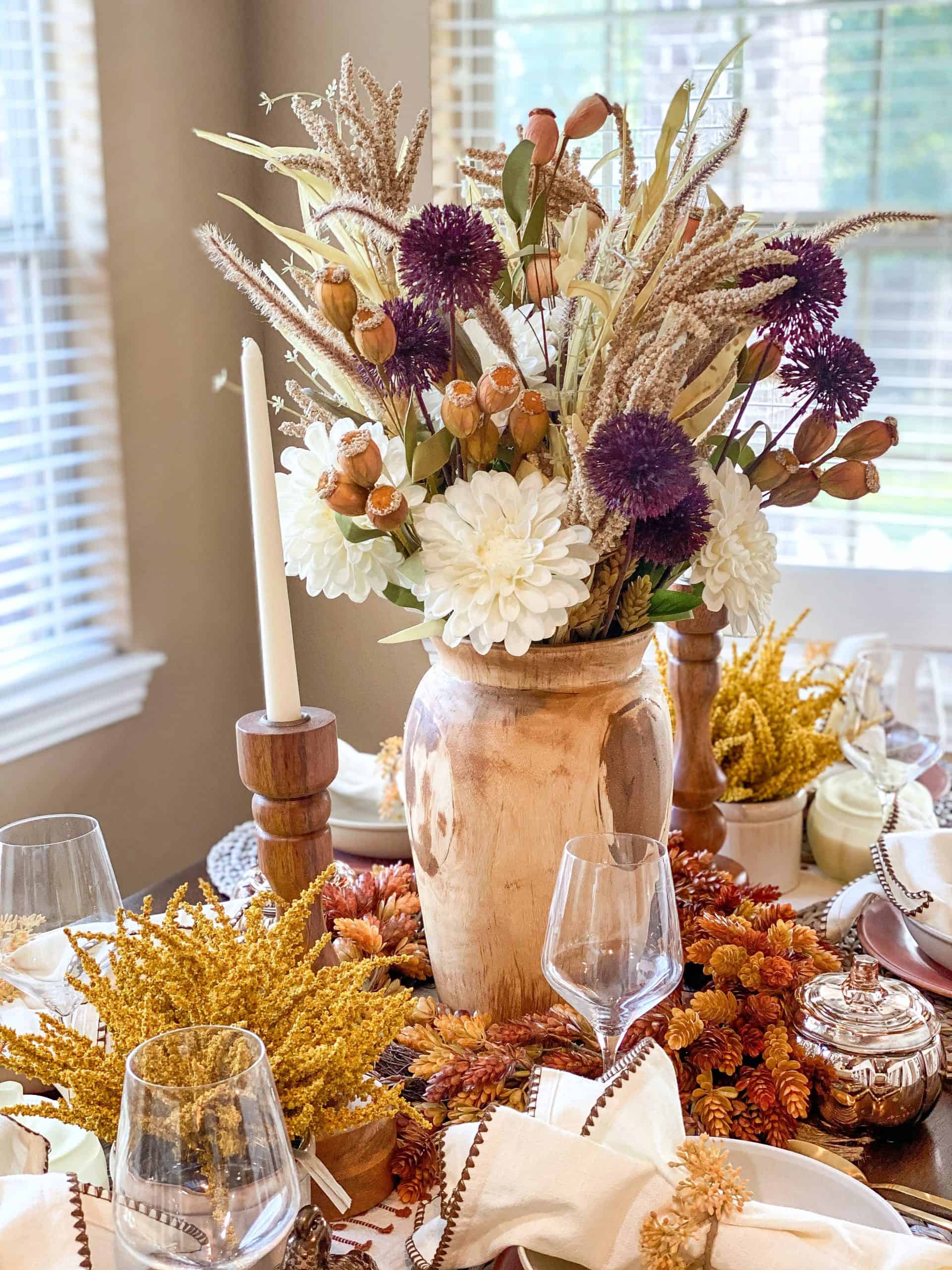 Fall Table Decor by popular Houston life and style blog, Glamorous Versatility: image of a dining table decorate with a Target table runner, straw place mats, linen napkins, wooden candle stick holders, white candle sticks, gold flatware, wooden vase, dried flowers, faux flowers, ceramic plates, ceramic bowls, and wine glasses. 