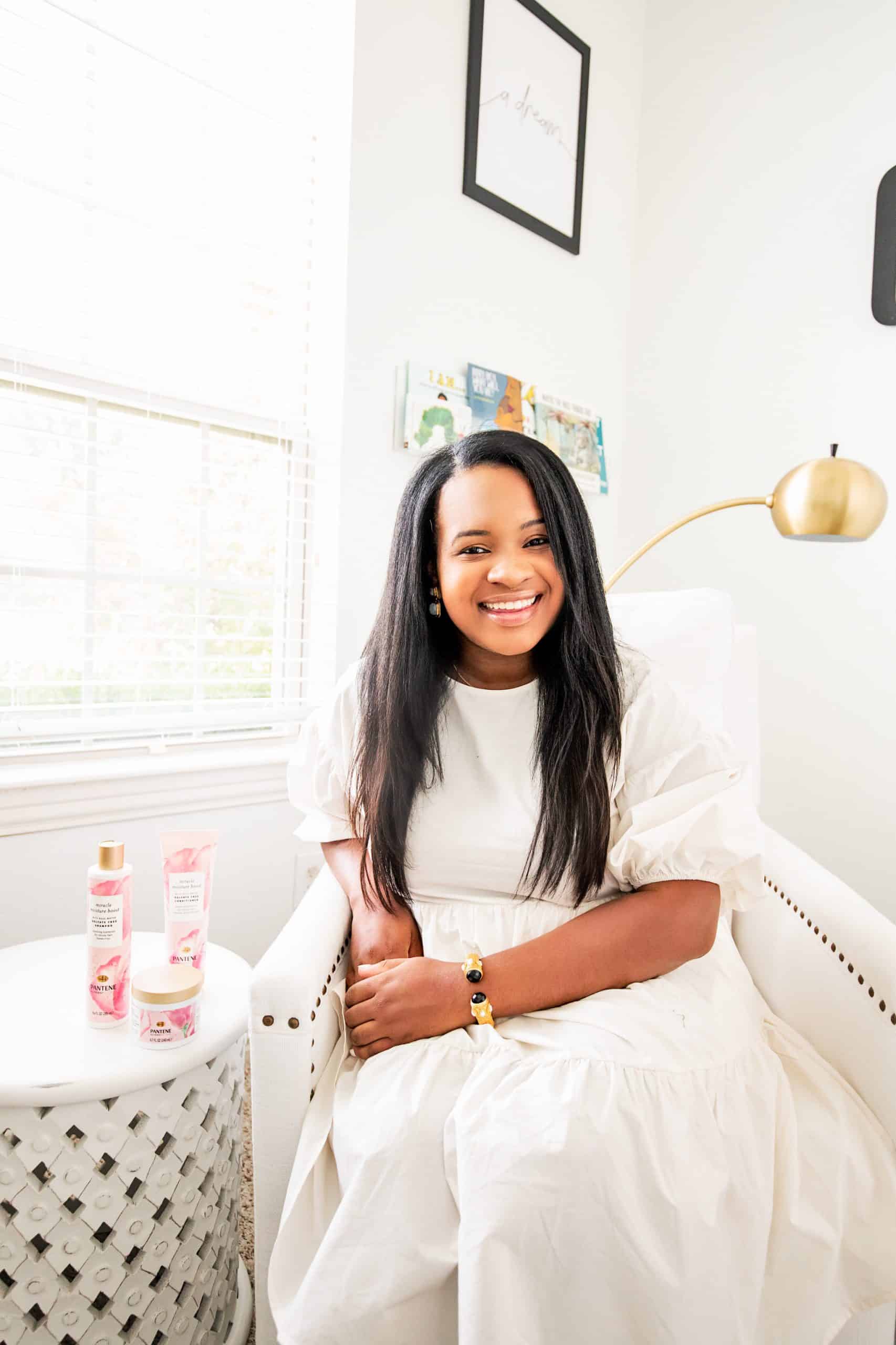 Self Confidence Tips by popular Dallas lifestyle blog, Glamorous Versatility: image of a woman wearing a white dress and sitting in a white rocking chair next to Pantene Miracle Moisture Boost hair products. 