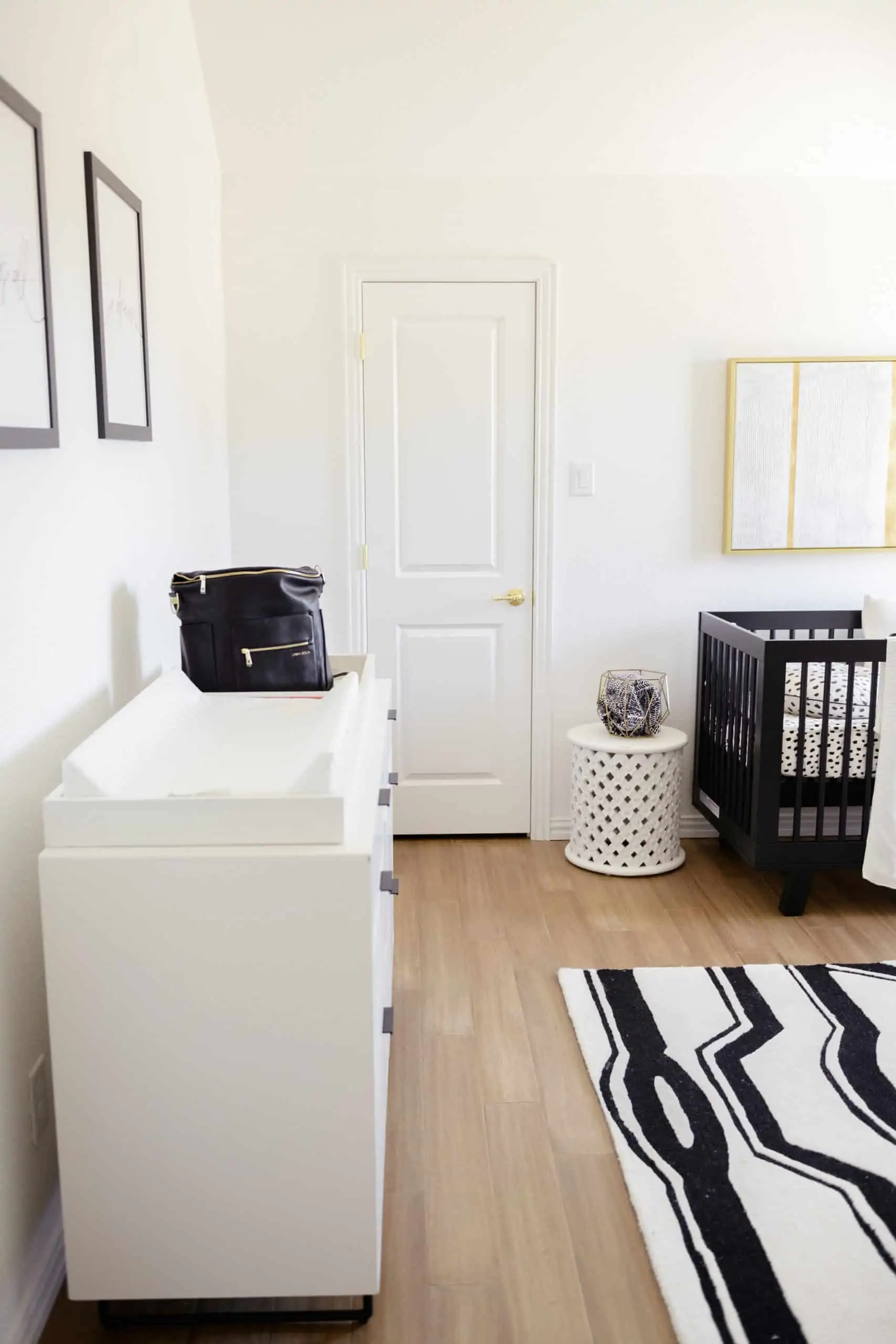 Wood Floor Installation by popular Dallas life and style blog, Glamorous Versatility: image of a boys room with light wood floors, black light fixture, black crib, black and white rug, white dresser, and white glider chair. 