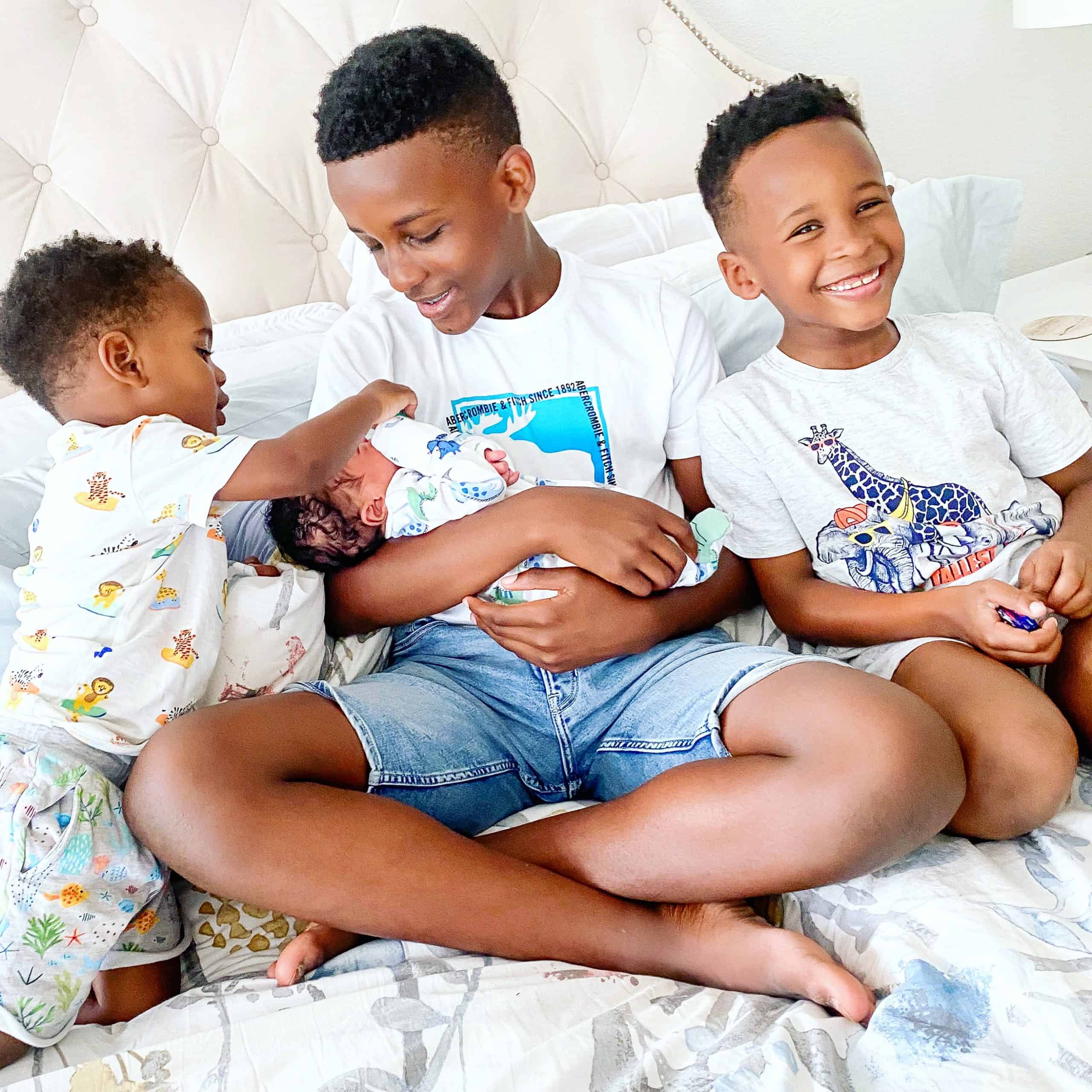 Birth Story by popular Dallas motherhood blog, Glamorous Versatility: image of three young boys holding a newborn baby boy. 