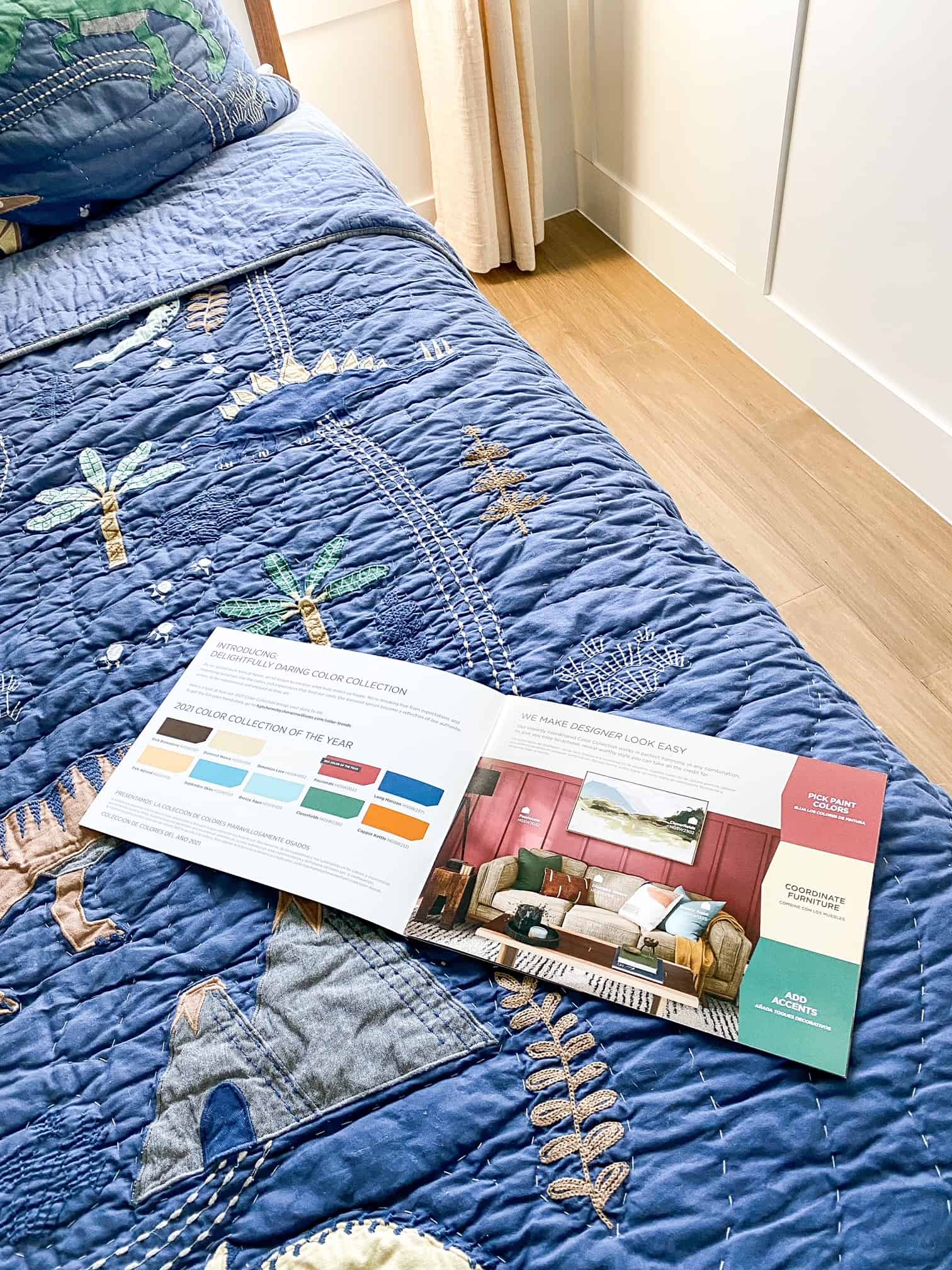 Bedroom Paint Colors by popular Dallas life and style blog, Glamorous Versatility: image of a paint catalogue on a bed with dinosaur bedding. 